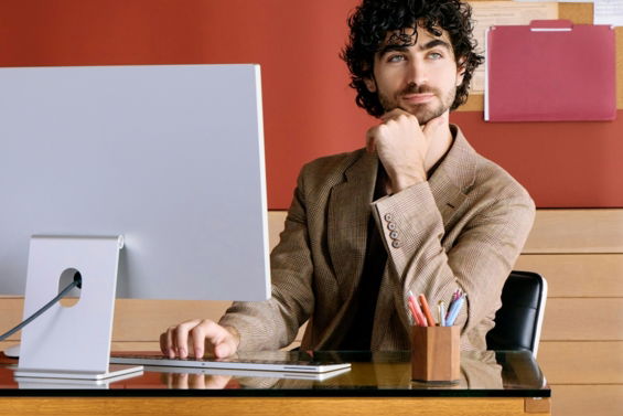 Man sitting at desk with computer, resting chin